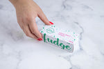Load image into Gallery viewer, A white fudge box sits on a neutral background. Paint splashes in hunter green and pink surround a messy circled logo for The Counter and the words &#39;Coco Malt fudge&#39; are written in cerise pink block lettering. On the topside of the box - large hunter green lettering states &#39;fudge&#39; and is surrounded by hunter green and cerise pink paint splashes. A manicured hand with red nail polish grabs the box.

