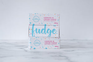 Three white boxes are stacked on a neutral background. Paint splashes in bright blue and pink surround a messy circled logo for The Counter in the first and third box, and the words 'Cookies & Cream fudge with dark chocolate' are written in cerise pink block lettering. The middle box has large, cursive font in bright blue stating the word 'fudge' on it.