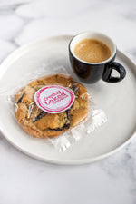 Load image into Gallery viewer, Salted dark chocolate cookies in branded packaging with an espresso alongside
