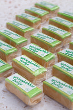 Load image into Gallery viewer, Bars of springbokkie fudge with green and white packaging on a textured surface
