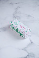 Load image into Gallery viewer, A white box sits on a neutral background. Large hunter green lettering states &#39;fudge&#39; and is surrounded by hunter green and cerise pink paint splashes. The other side of the box that is visible has Paint splashes in hunter green and pink surround a messy circled logo for The Counter and the words &#39;Coco Malt fudge&#39; are written in cerise pink block lettering.
