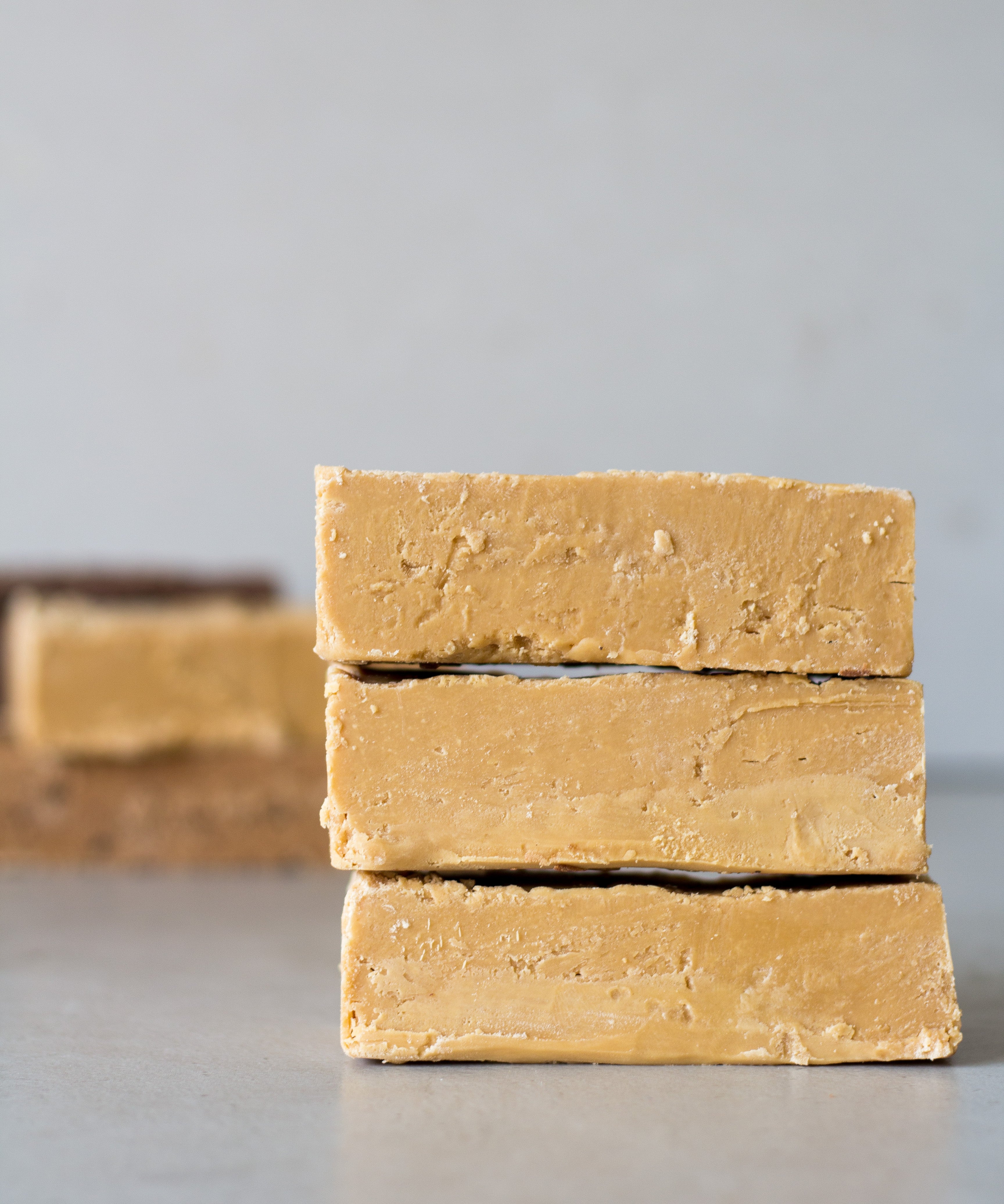Three large bars of peanut butter fudge are stacked on top of each other .