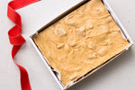Load image into Gallery viewer, One kilogram slab of gingerbread fudge in a sturdy white cardboard tray - finished with a red saddle stitch ribbon.
