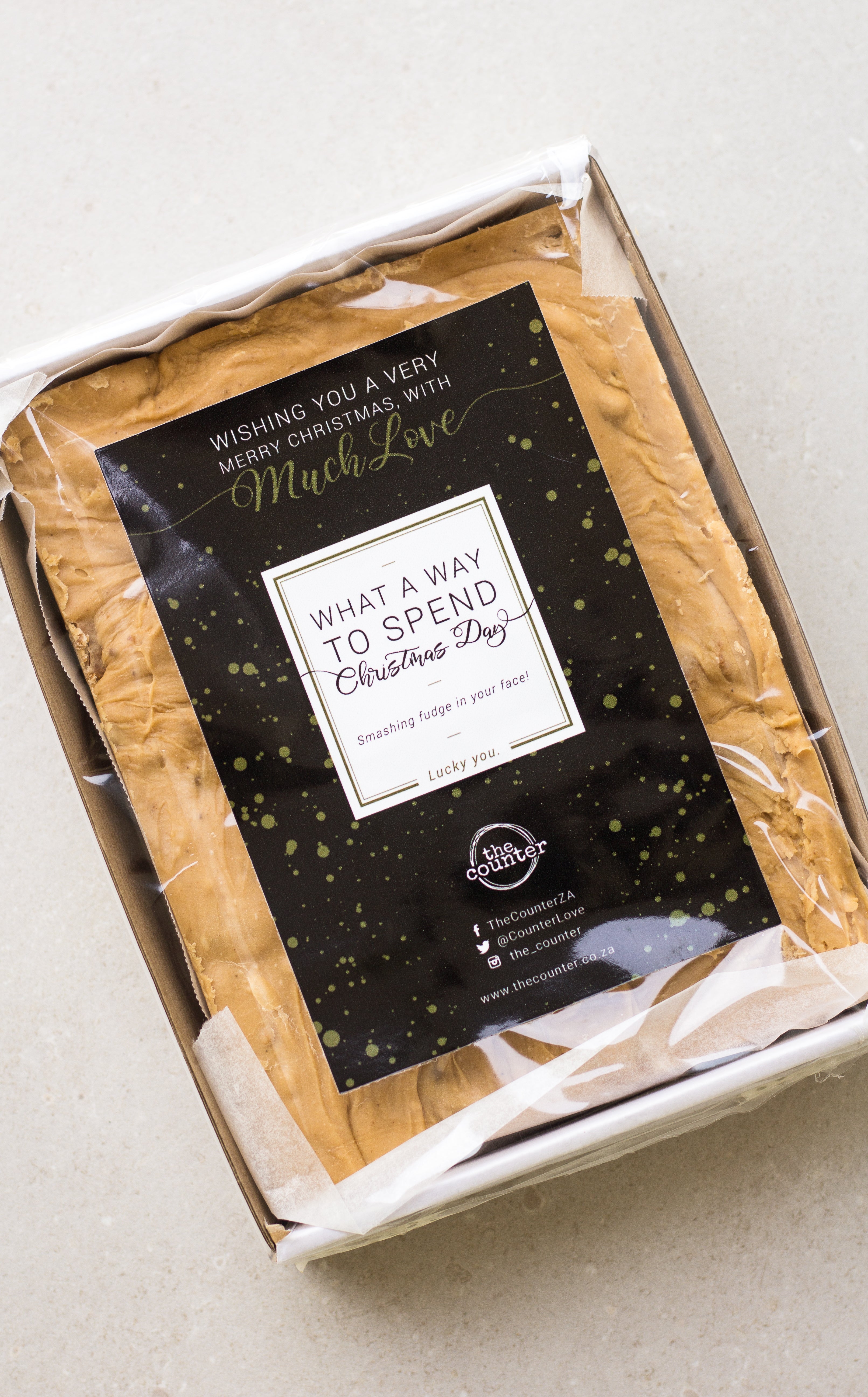 One kilogram slab of gingerbread fudge in a sturdy white cardboard tray - finished with a black and gold 'Merry Christmas' sticker.