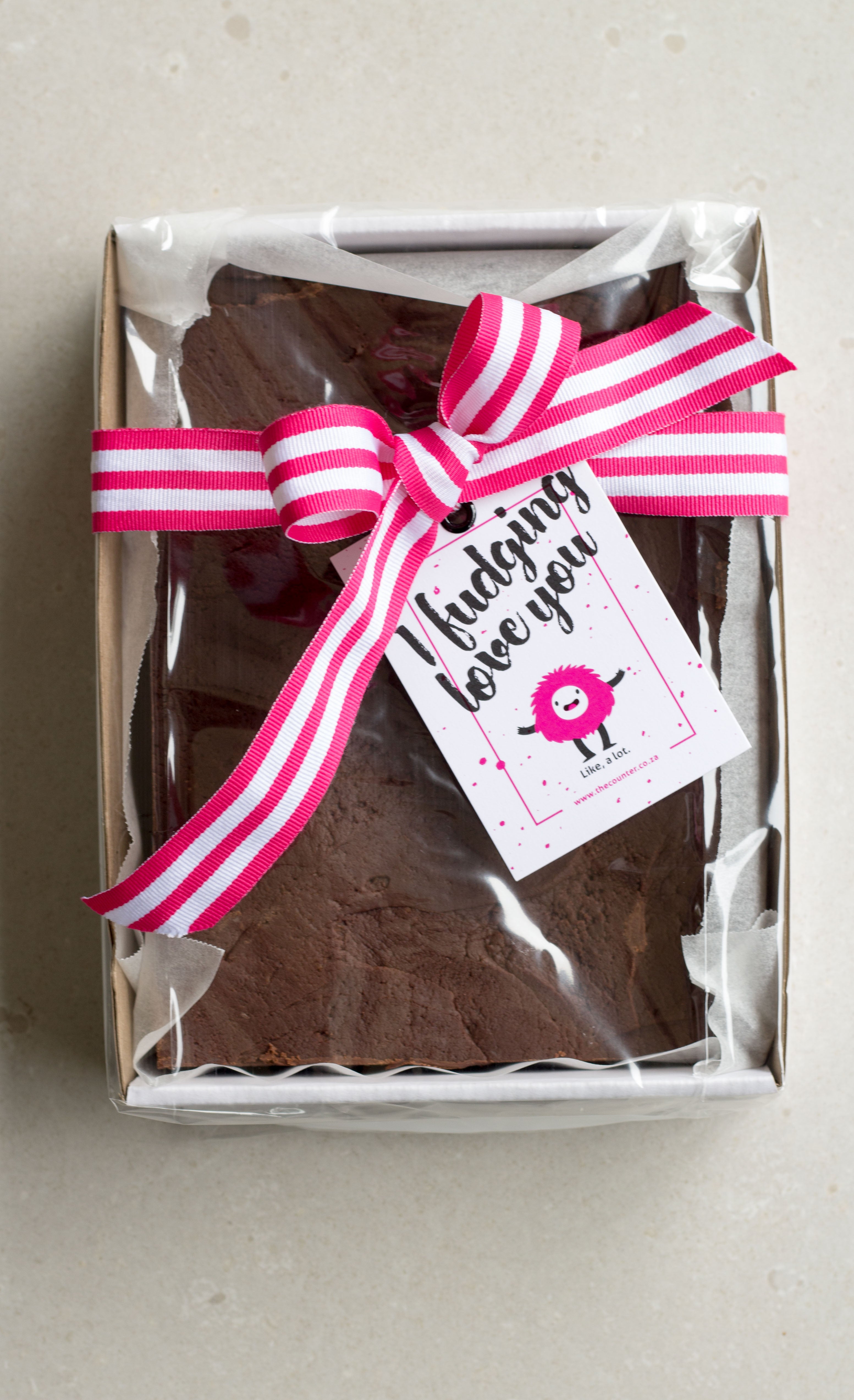 One kilogram cookies and cream fudge slab in a sturdy cardboard tray, finished with a pink striped ribbon and 'I Fudging Love You' swing tag