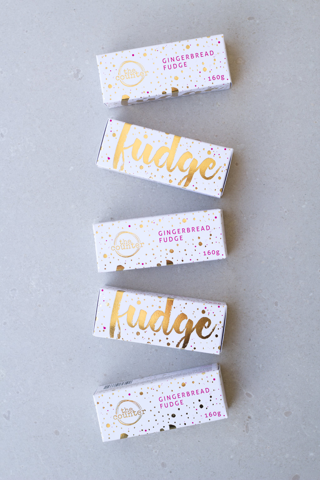 Gold foiled white box filled with gingerbread fudge - five in a row, at an angle.