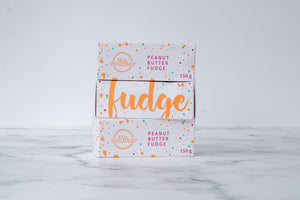 Three white boxes are stacked on a neutral background. Paint splashes in orange and pink surround a messy circled logo for The Counter on the first and third box; and the words ‘Peanut Butter Fudge' are written in cerise pink block lettering. The middle box has large, orange cursive writing on it stating 'fudge'.