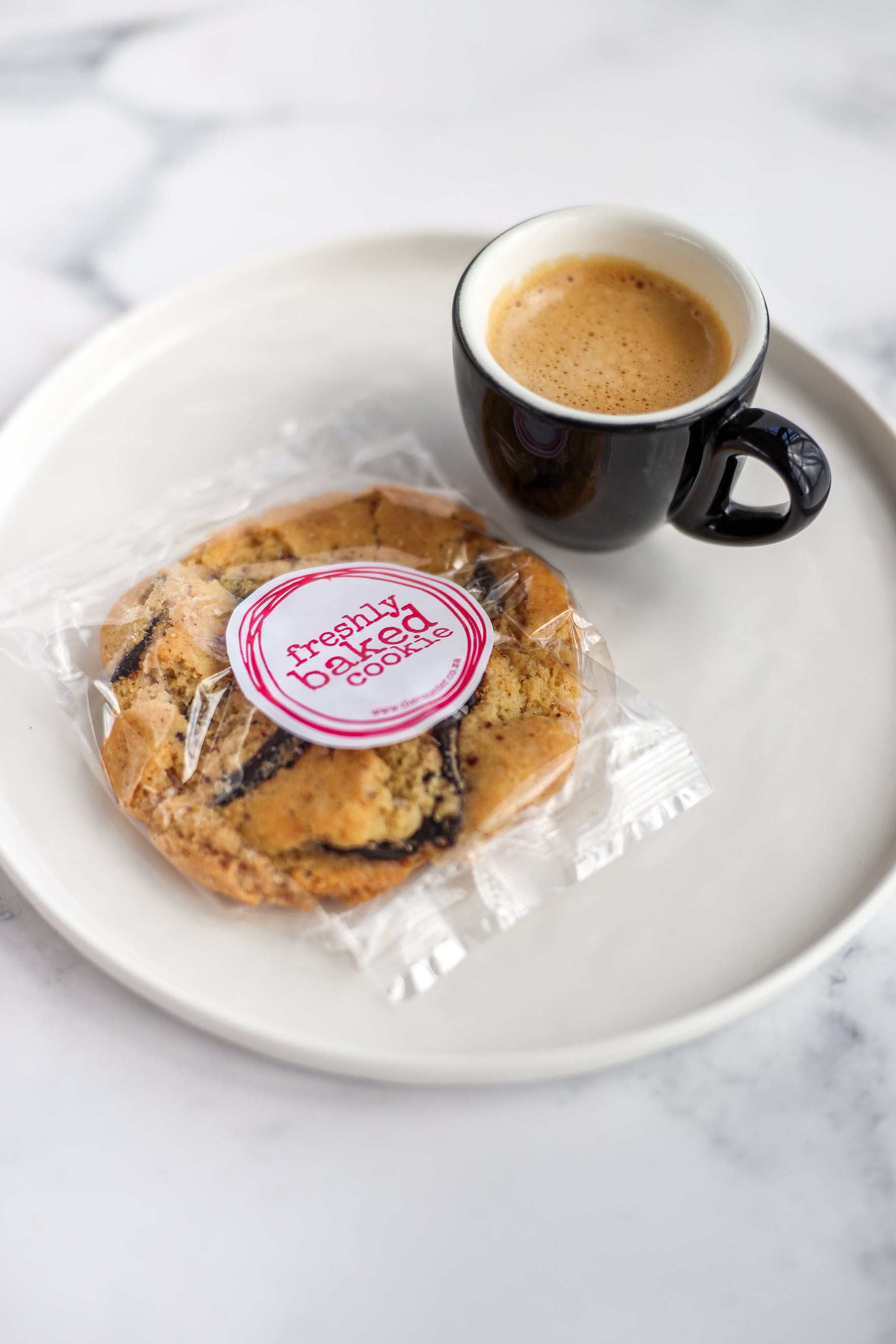 Salted dark chocolate cookies in branded packaging with an espresso alongside