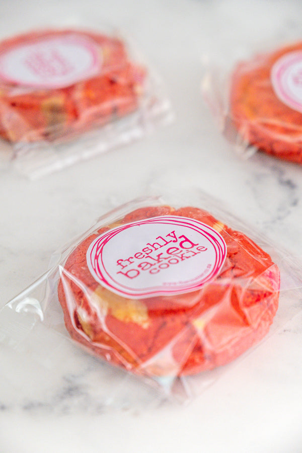 Three red velvet cookies in branded packaging